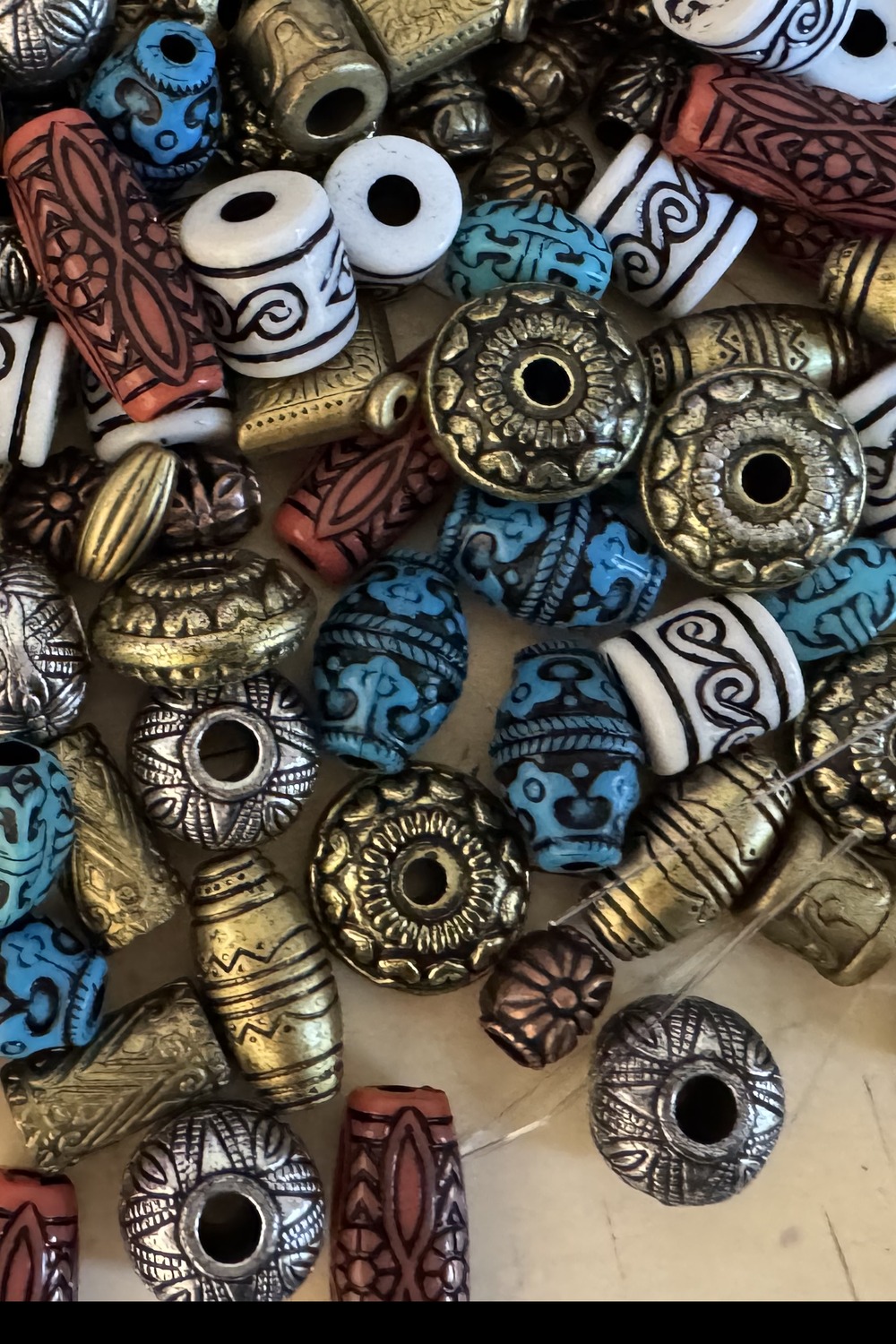 A pile of antique pattern beads in turquoise, terracotta, gold and silver — collected over decades.
