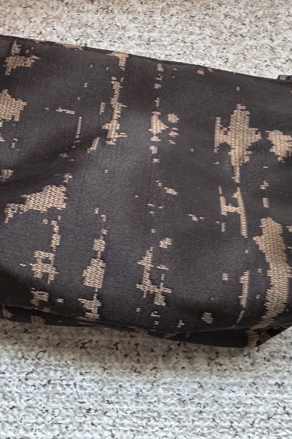 Macro detail of black silk damask fabric with gold weave — held since the 1970s.