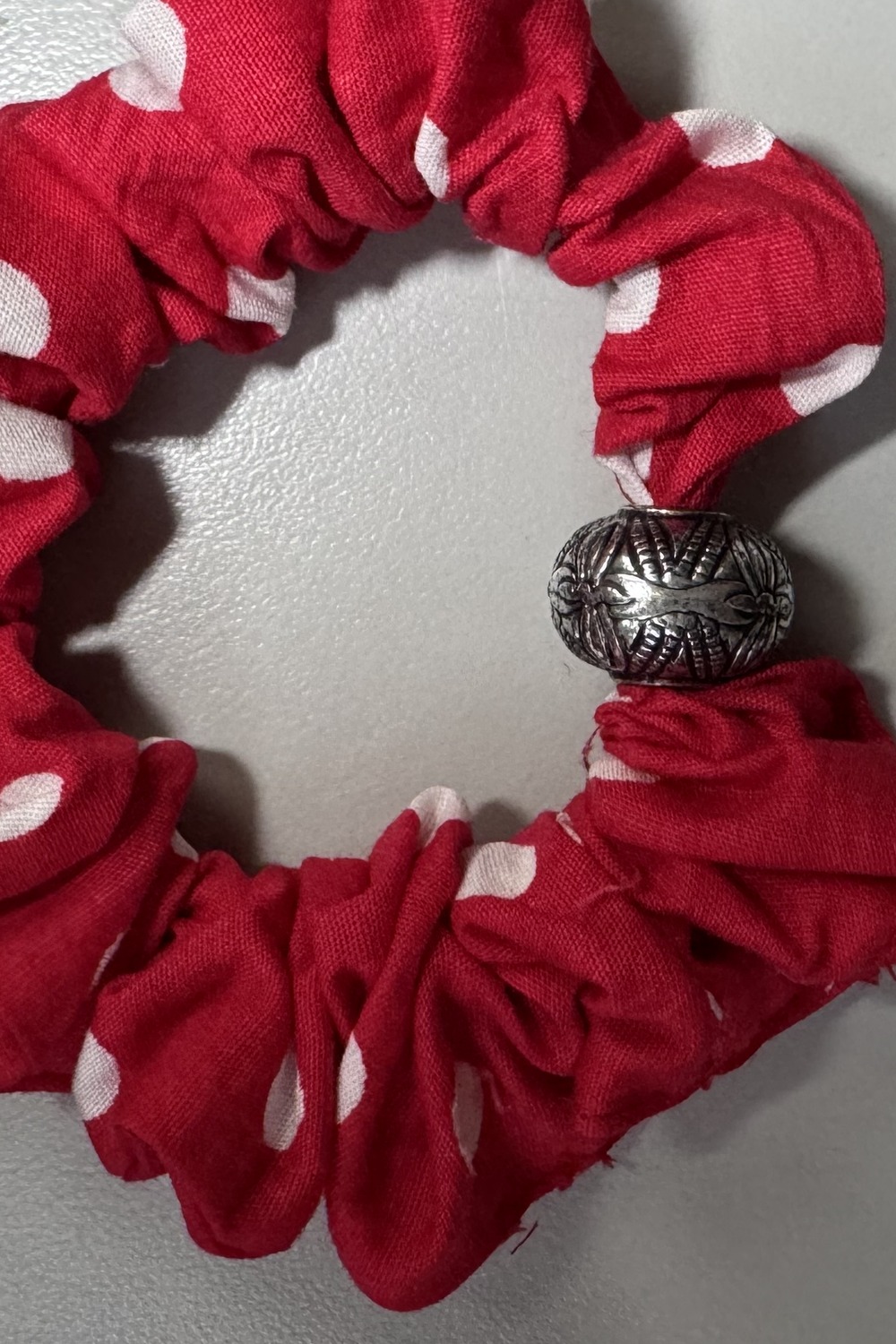 Red and white polka-dot fabric scrunchie with an antique silver pattern bead.