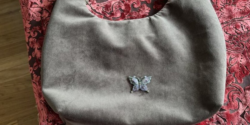 Pewter grey velvet hobo bag with embroidered butterfly, photographed on coral pink damask velvet.